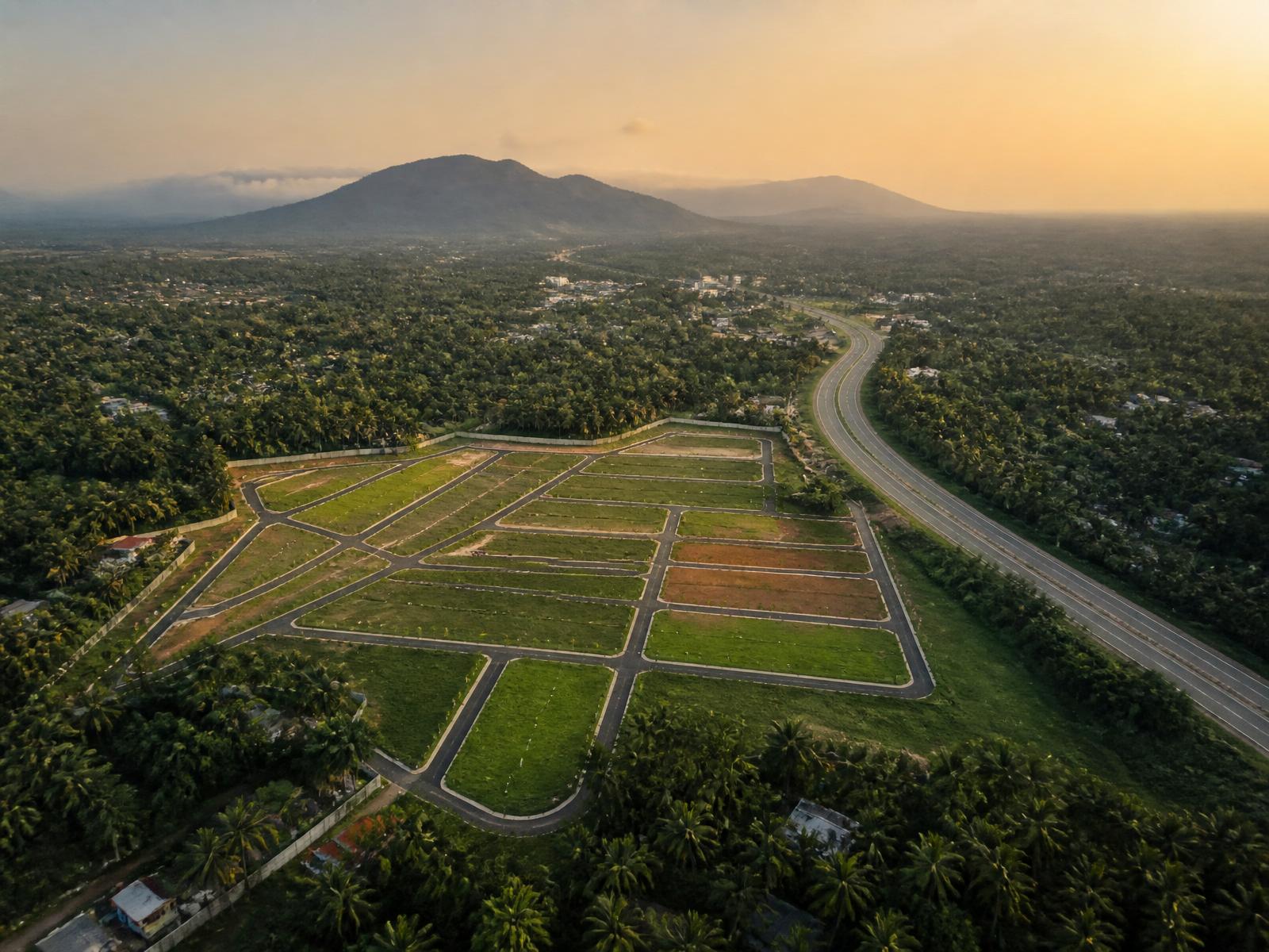 Aerial view of premium land plots at golden hour near city skyline